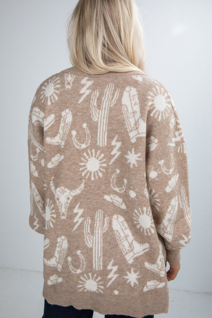 Person wearing a beige cardigan with white patterns on a plain background