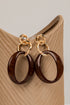 Pair of gold and brown hoop earrings on a wooden stand.