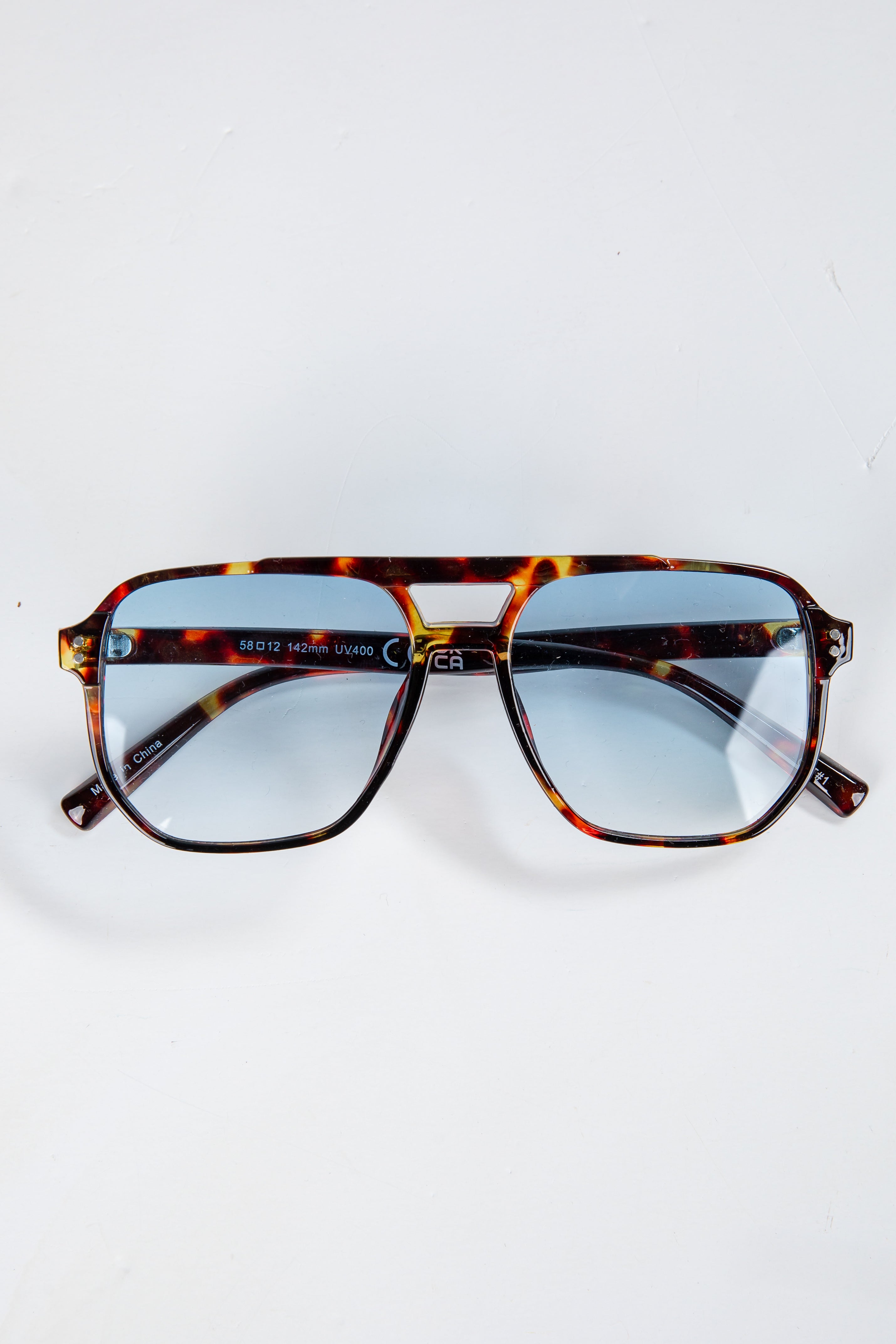 Tortoiseshell sunglasses with blue lenses on a white background
