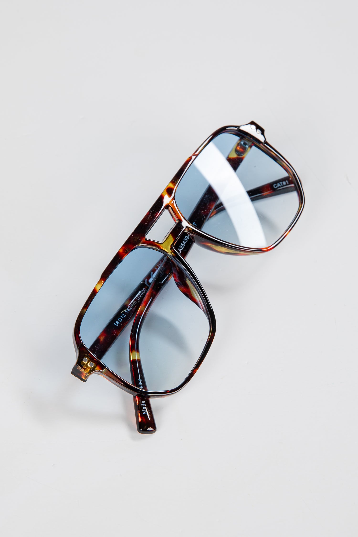 Tortoiseshell sunglasses with reflective lenses on a light gray background