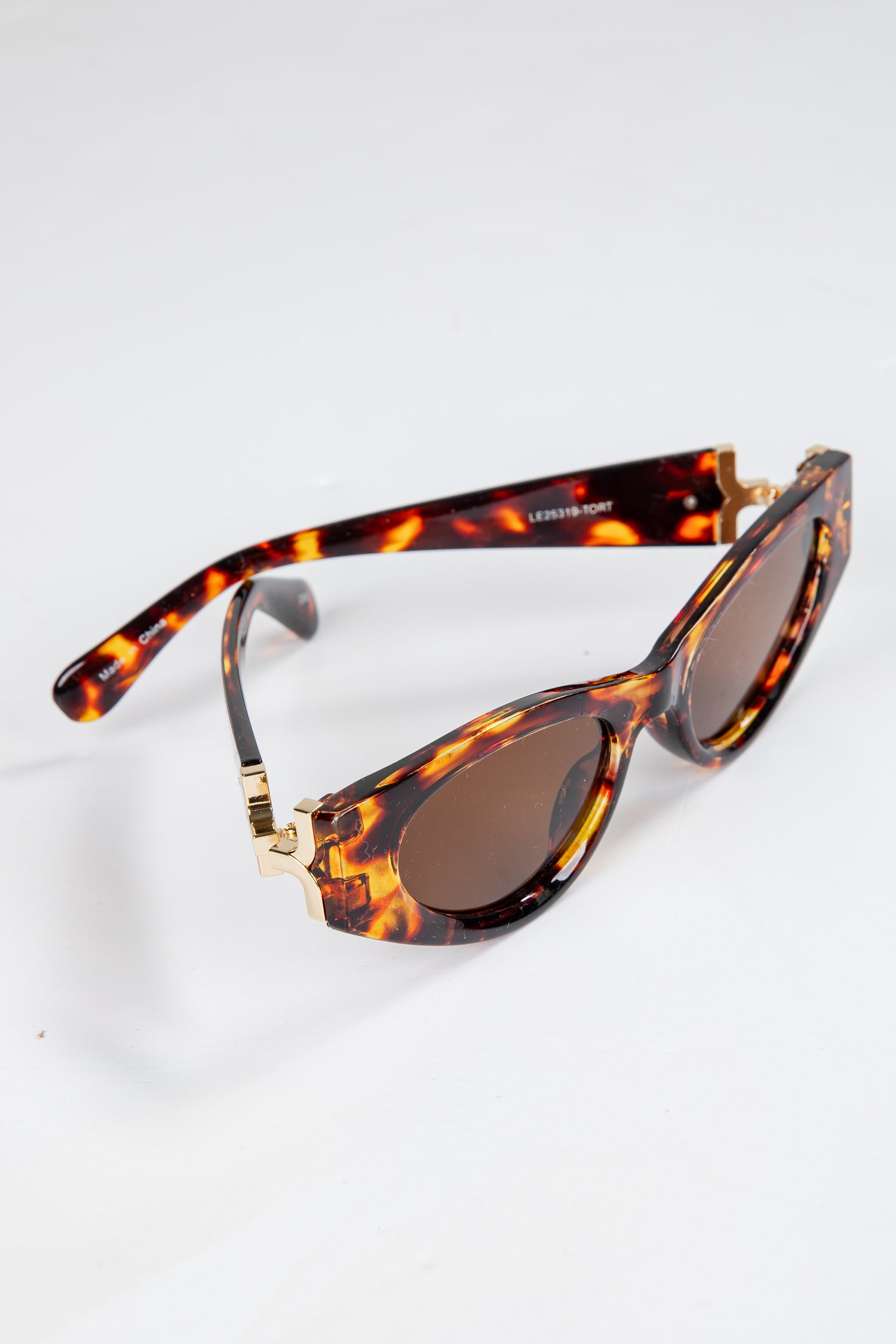Sunglasses with tortoiseshell frame and brown lenses on a white background