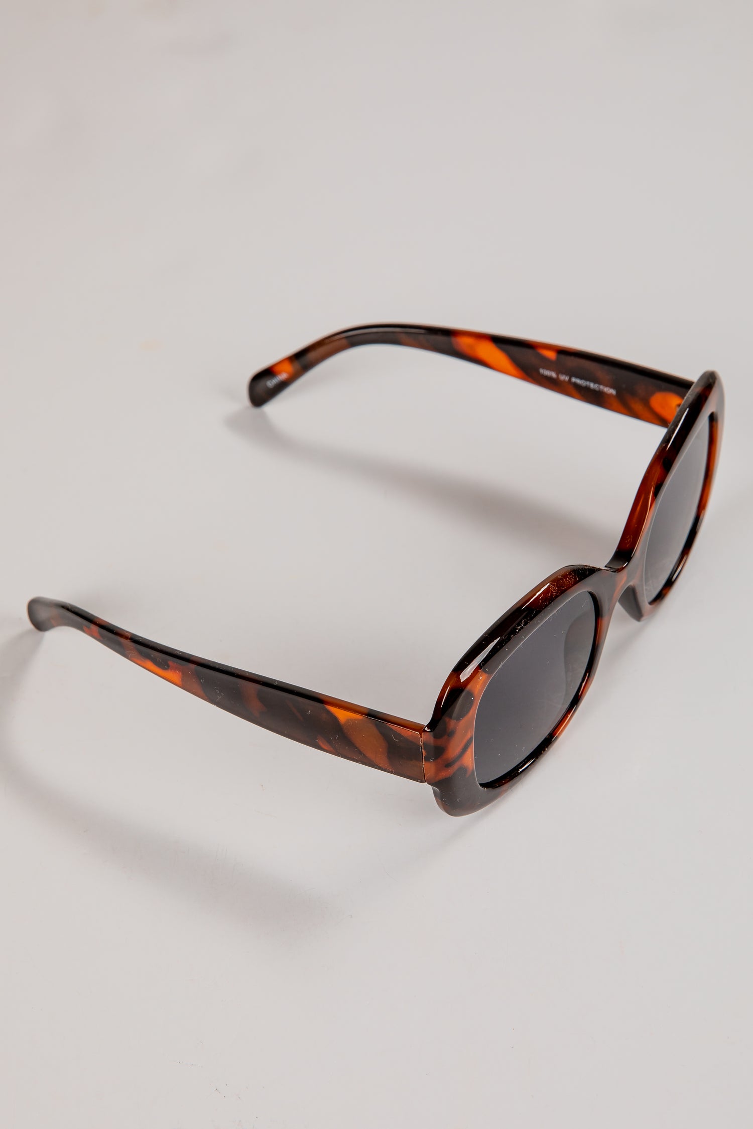 Sunglasses with tortoiseshell frame on a light gray background