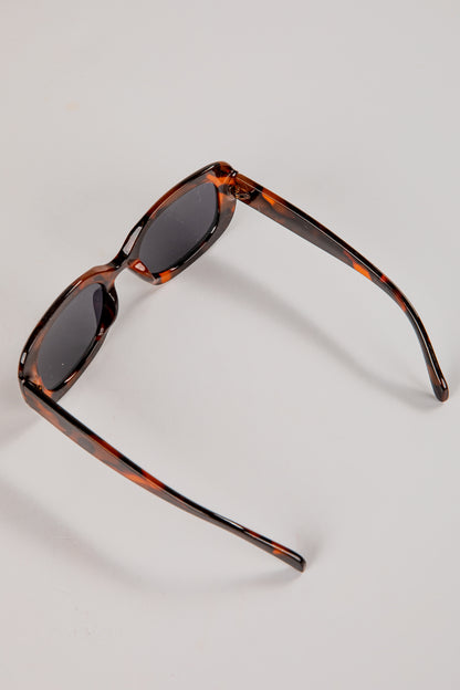 Sunglasses with tortoiseshell frame and dark lenses on a light gray background