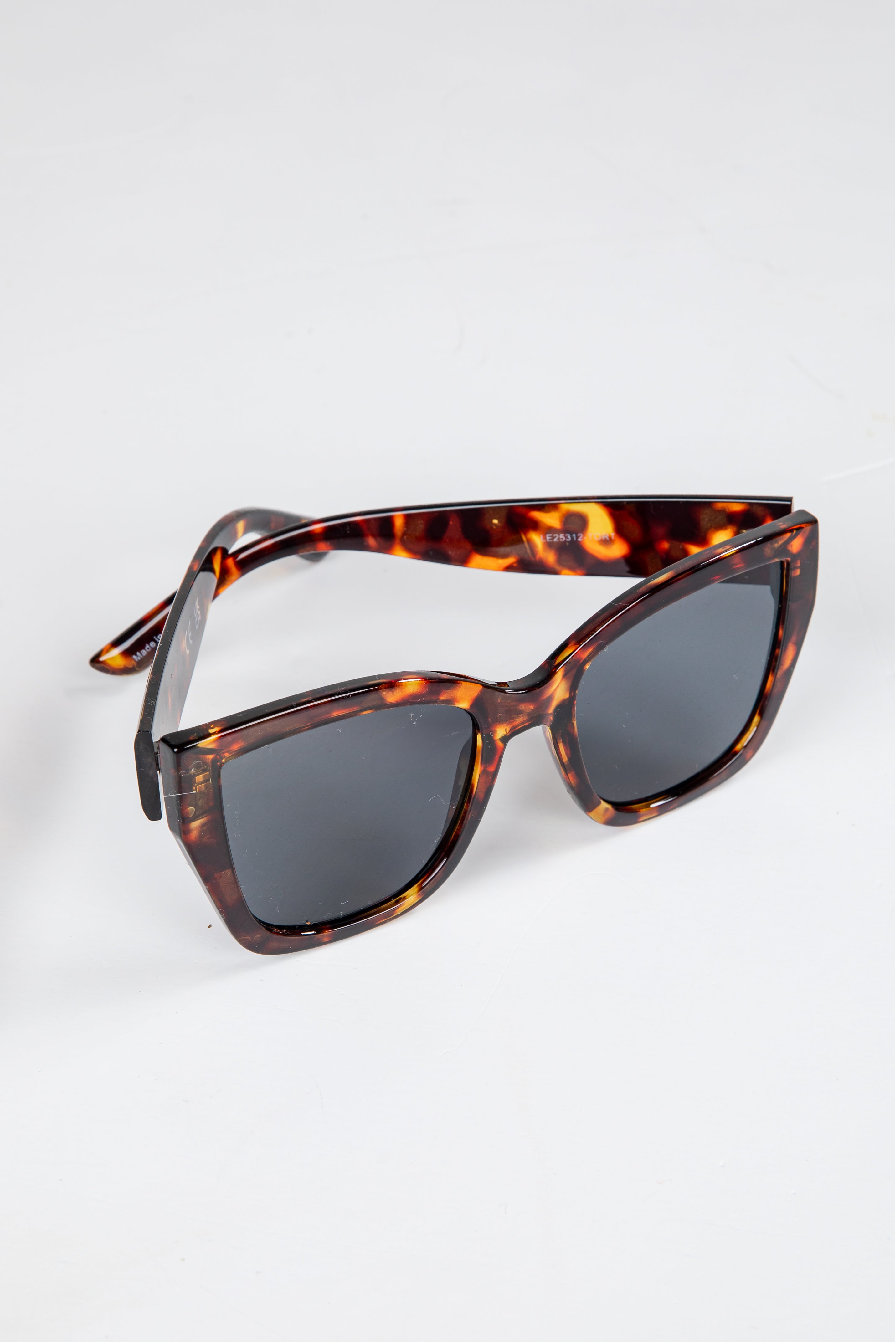 Tortoiseshell sunglasses with dark lenses on a white background