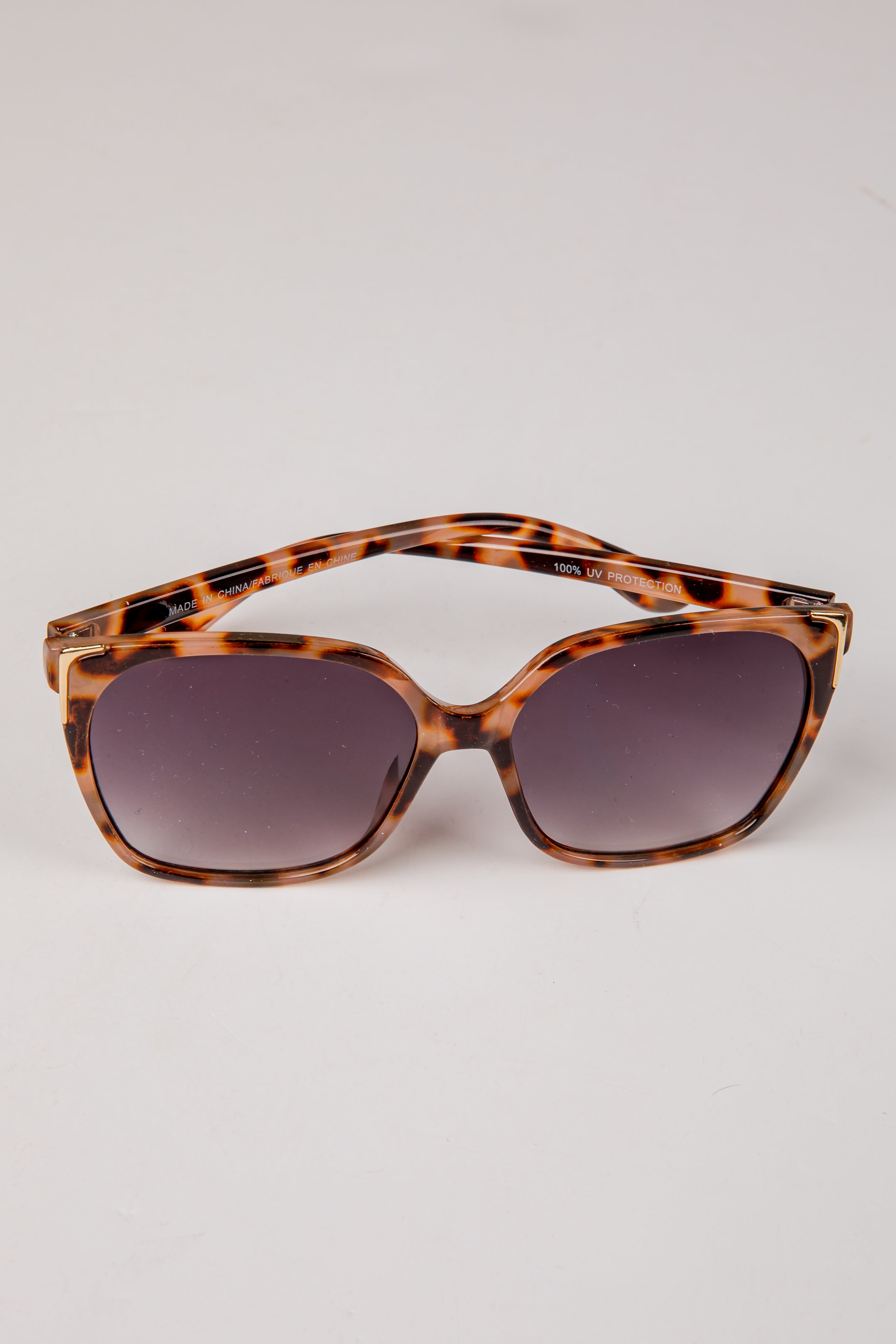 Tortoiseshell sunglasses with dark lenses on a light gray background