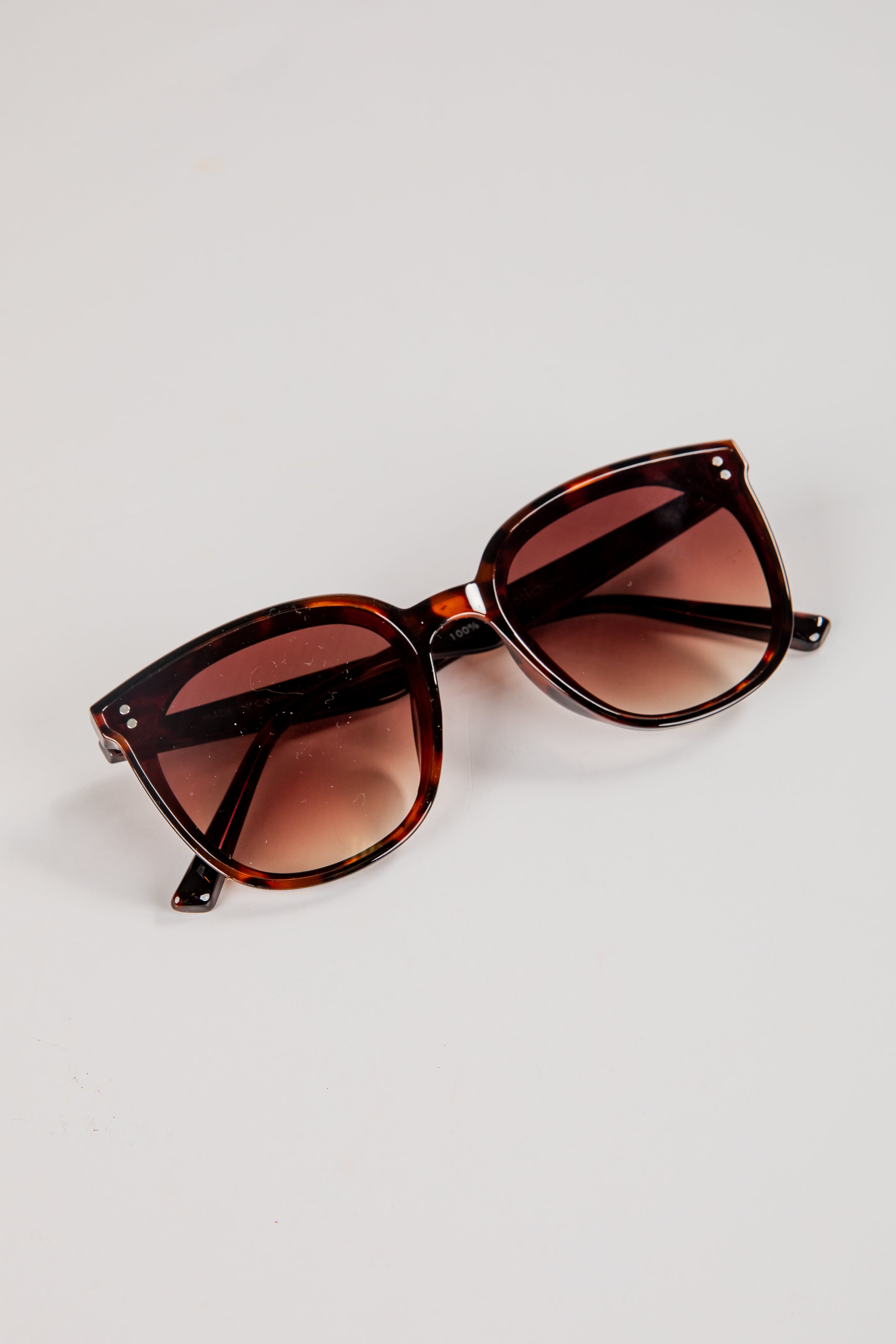 Sunglasses with brown gradient lenses on a light gray background