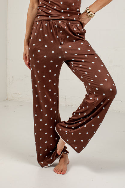 Brown wide-leg pants with a white polka dot pattern, shown on a model against a white studio background.