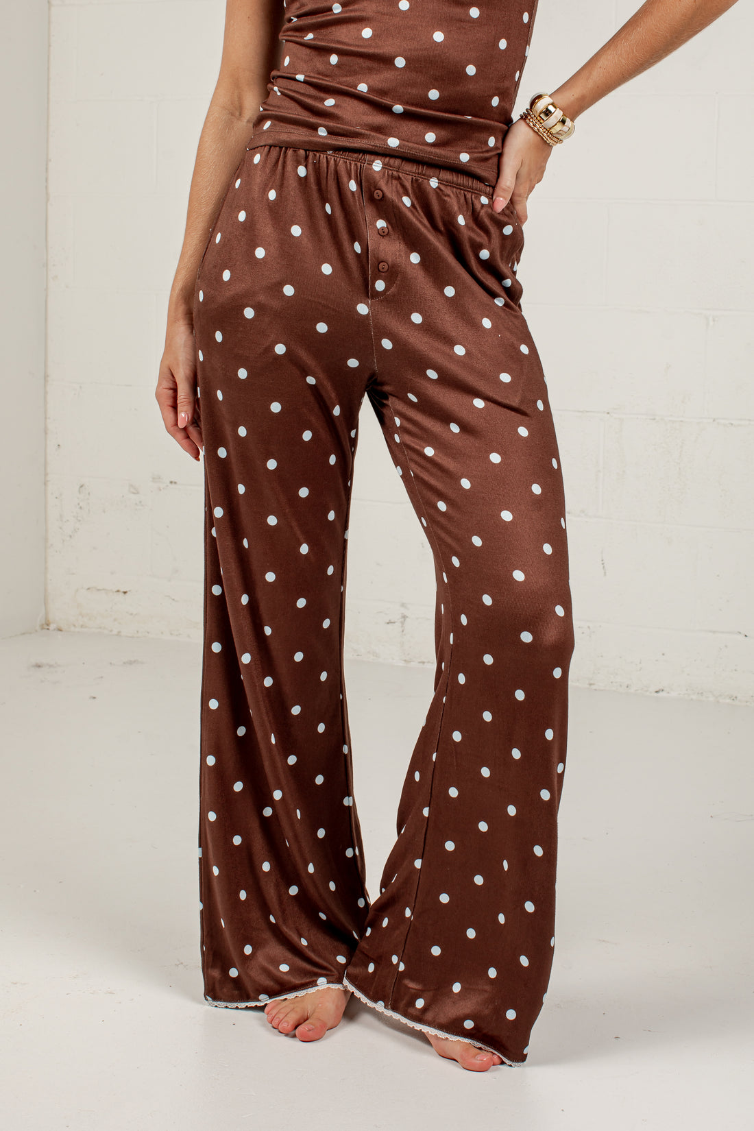 Brown wide-leg pants with a white polka dot pattern, shown on a model against a white studio background.