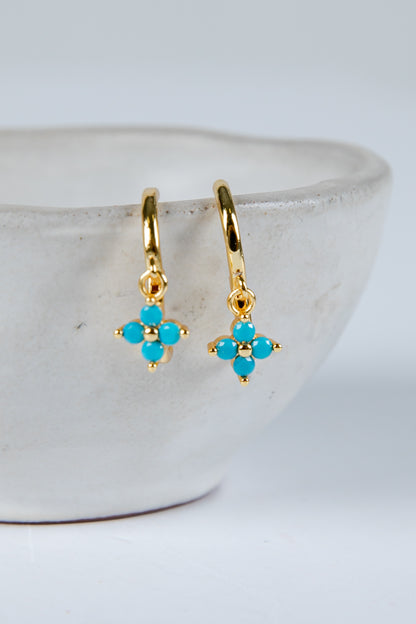 Gold earrings with turquoise stones on a white background