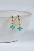Gold earrings with turquoise stones on a white background
