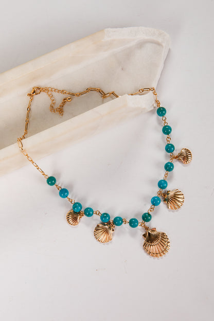 Necklace with turquoise beads and gold shell pendants on a white background