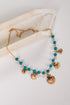 Necklace with turquoise beads and gold shell pendants on a white background
