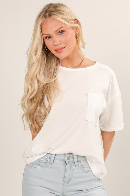 Woman wearing a white t-shirt and light blue jeans against a plain background