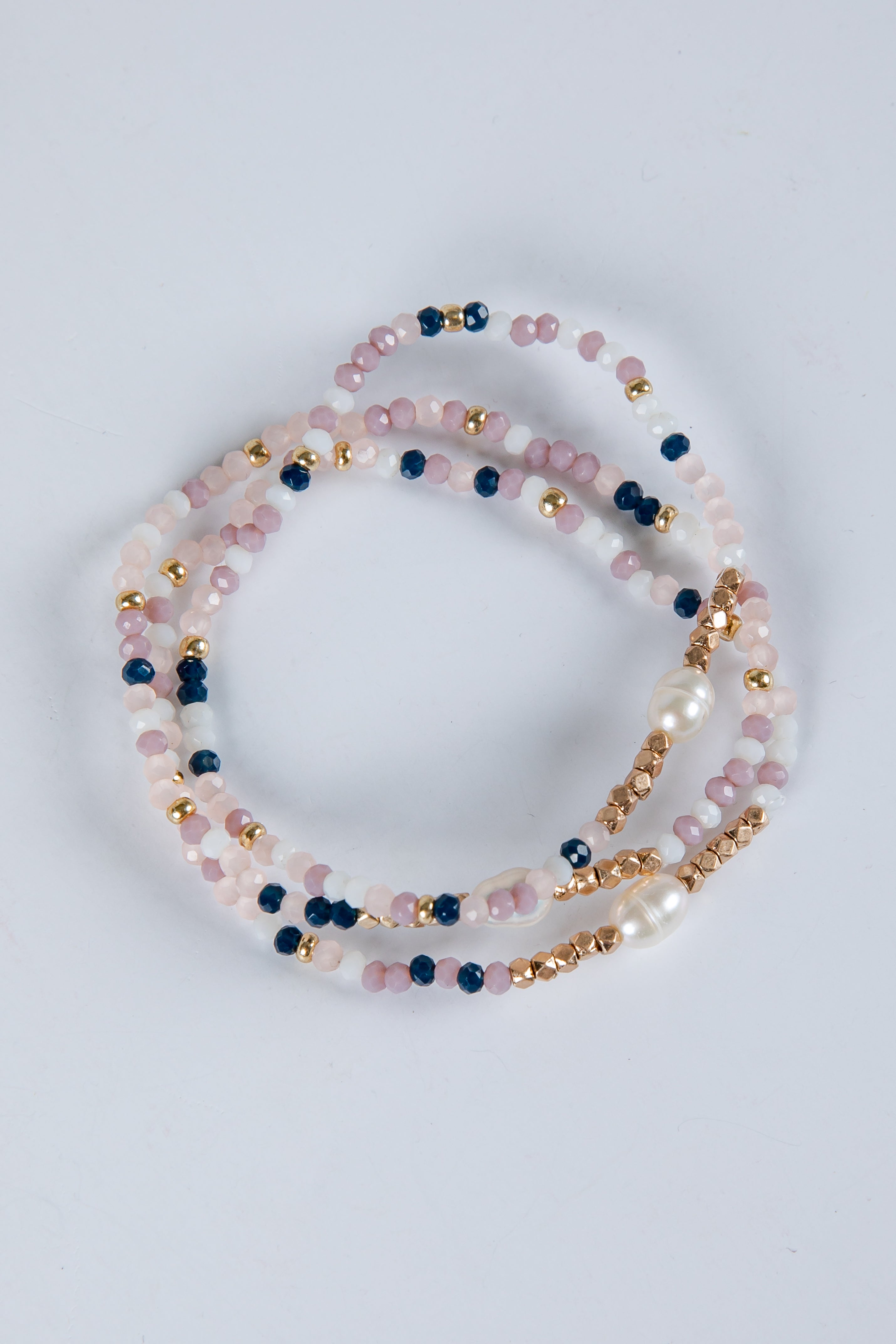 Set of beaded bracelets with pink, blue, and gold beads on a light gray background