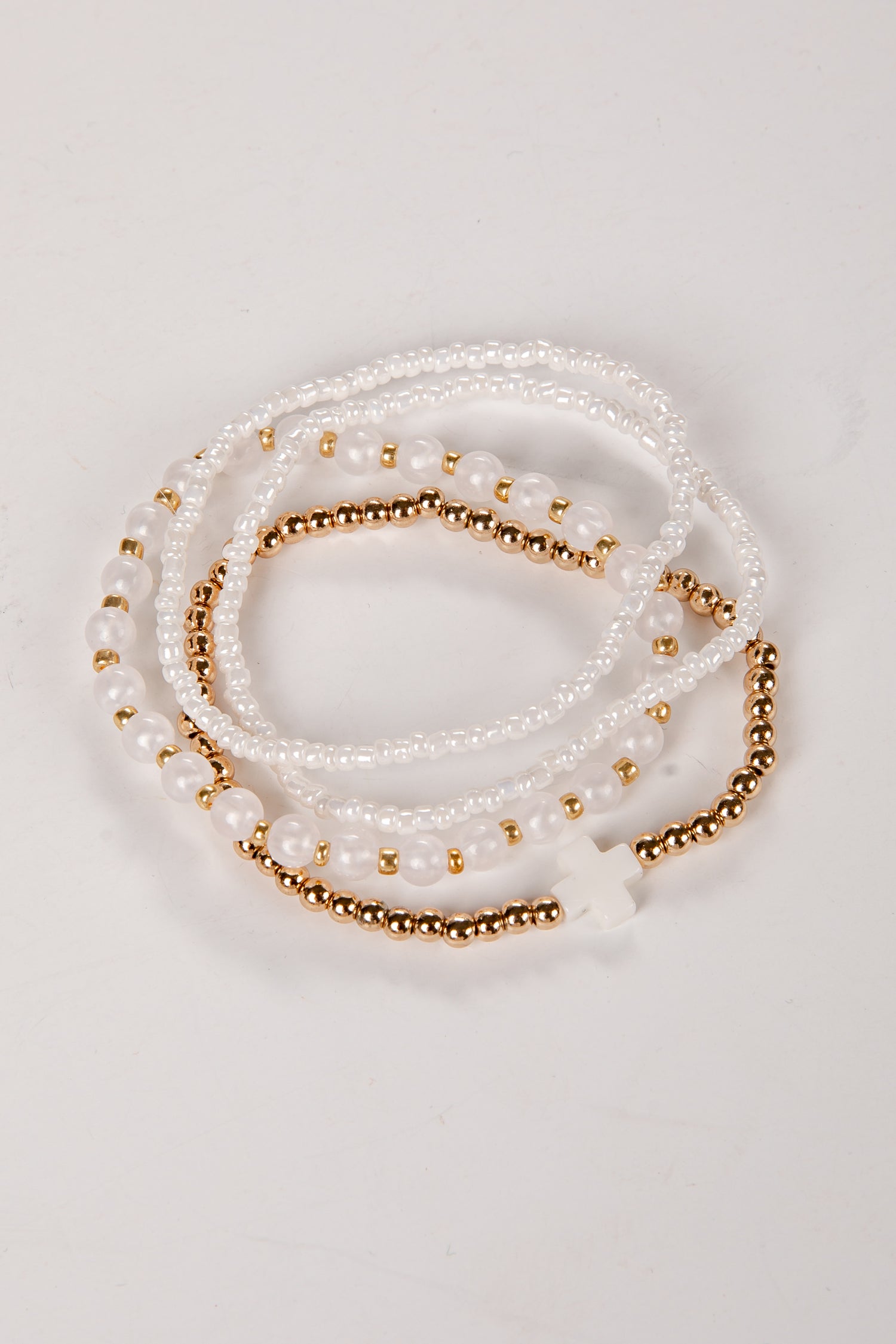 Set of pearl and gold beaded bracelets on a light background