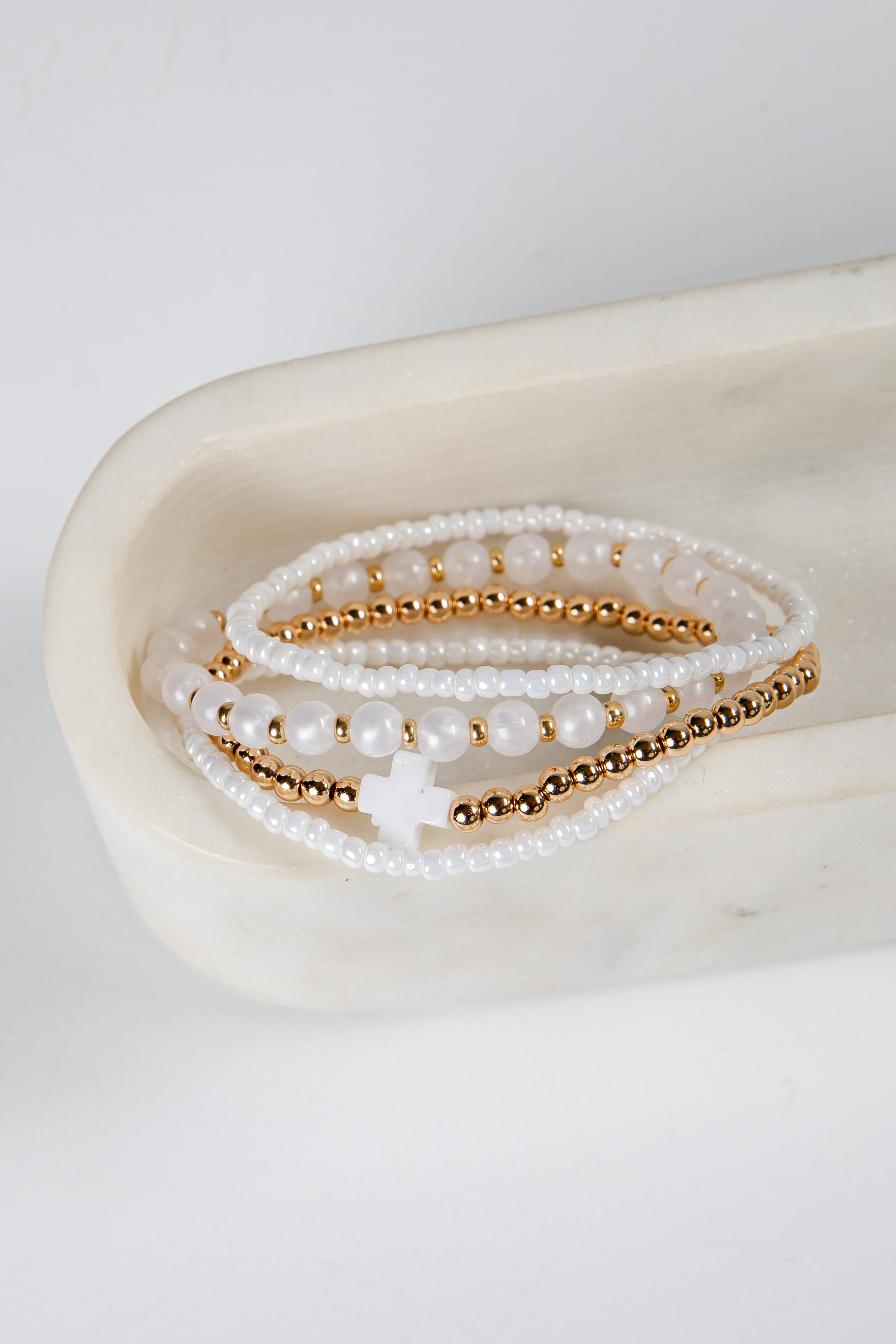 Set of pearl and gold beaded bracelets on a white surface