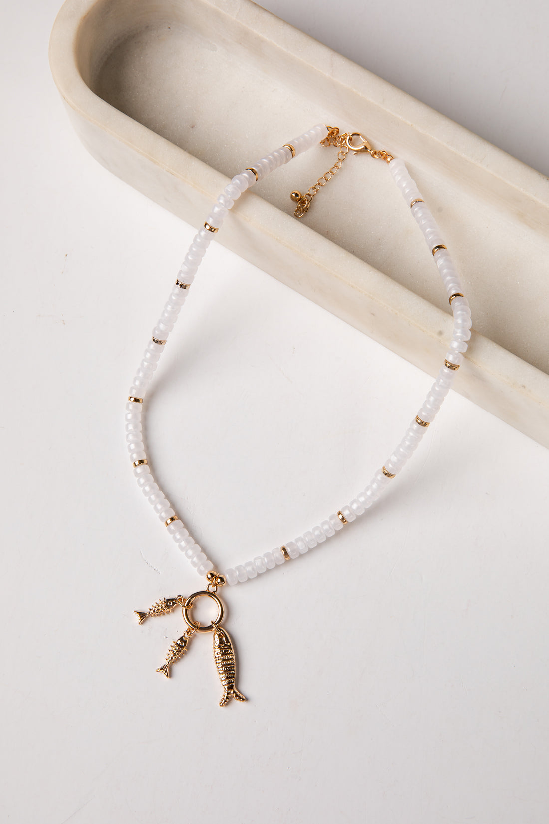 Necklace with fish charms on a white surface