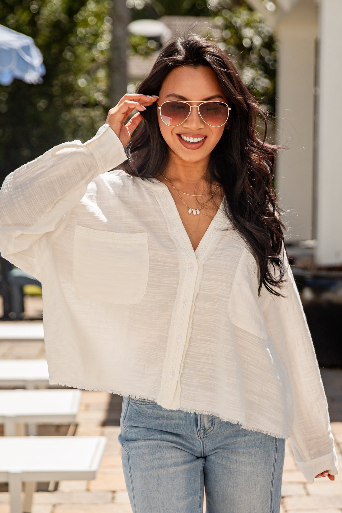 Woman wearing a light-colored blouse and sunglasses outdoors