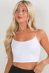 Woman wearing a white tank top against a plain background