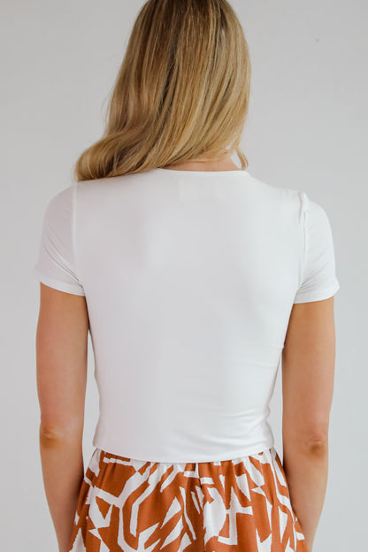 Person wearing a white t-shirt and patterned shorts on a plain background