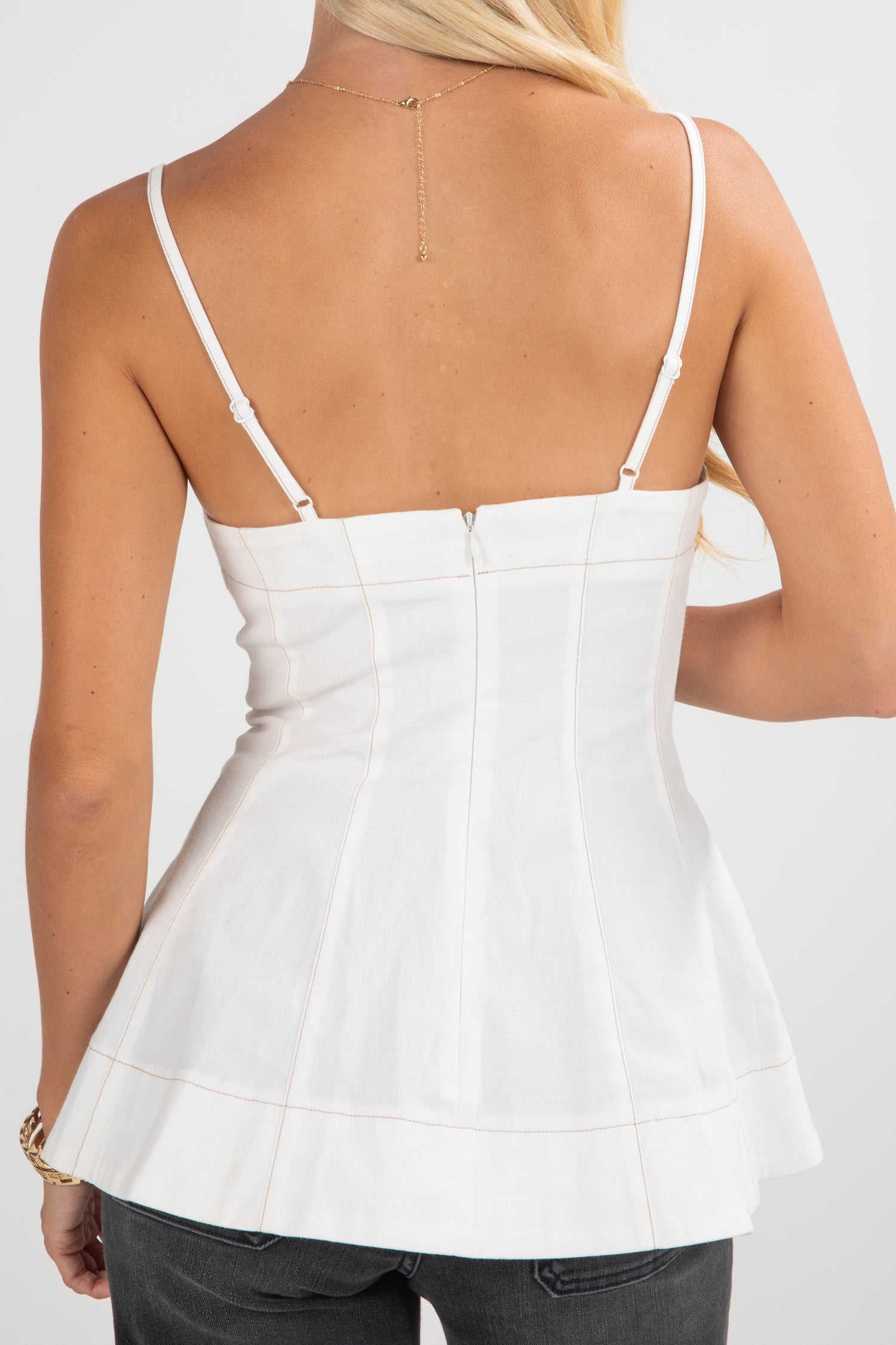 White peplum top worn by a person on a white background