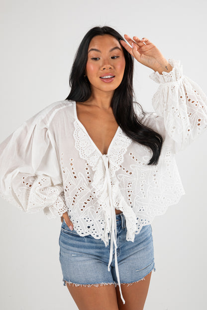 Woman wearing a white lace top and denim shorts on a white background