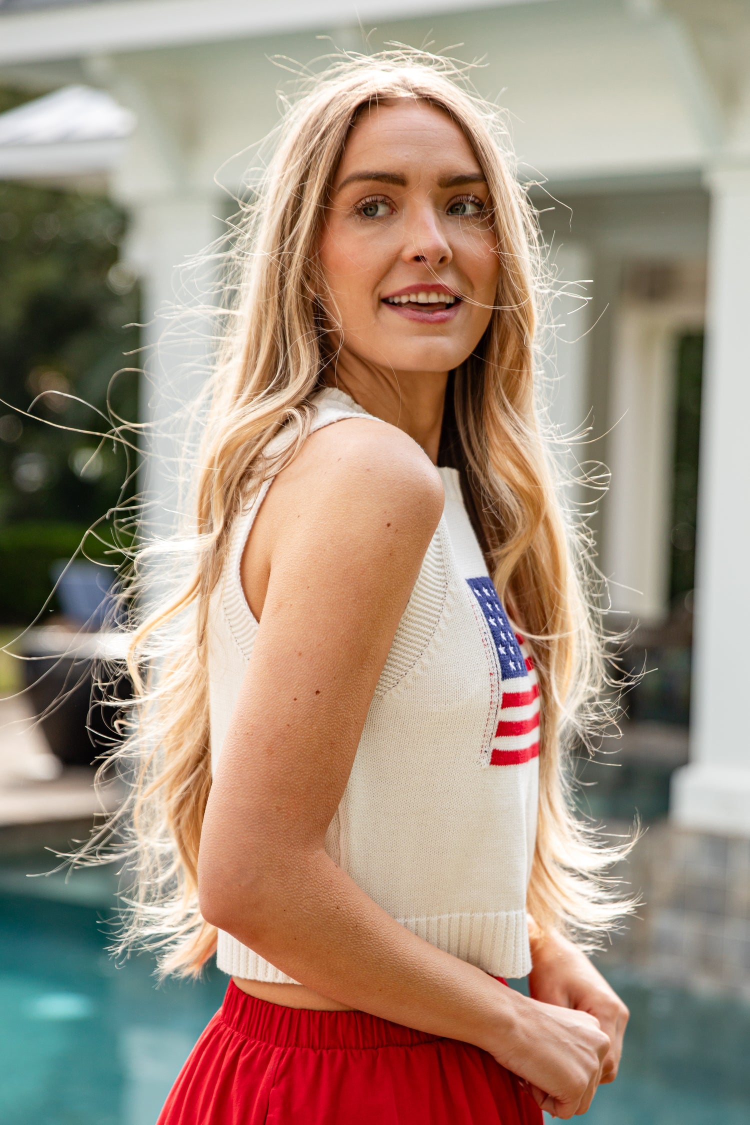 Woman wearing a sleeveless top with an American flag design outdoors.