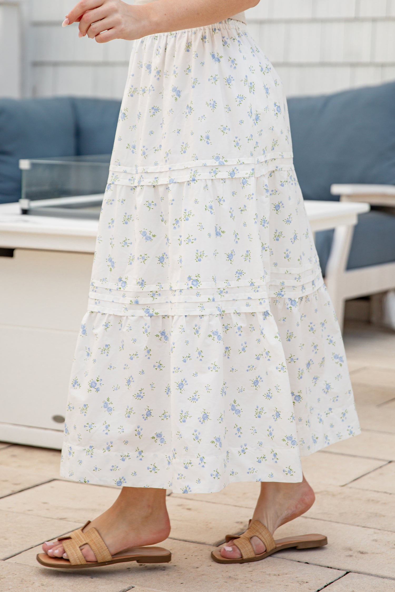 Person wearing a white floral dress standing on a wooden deck.