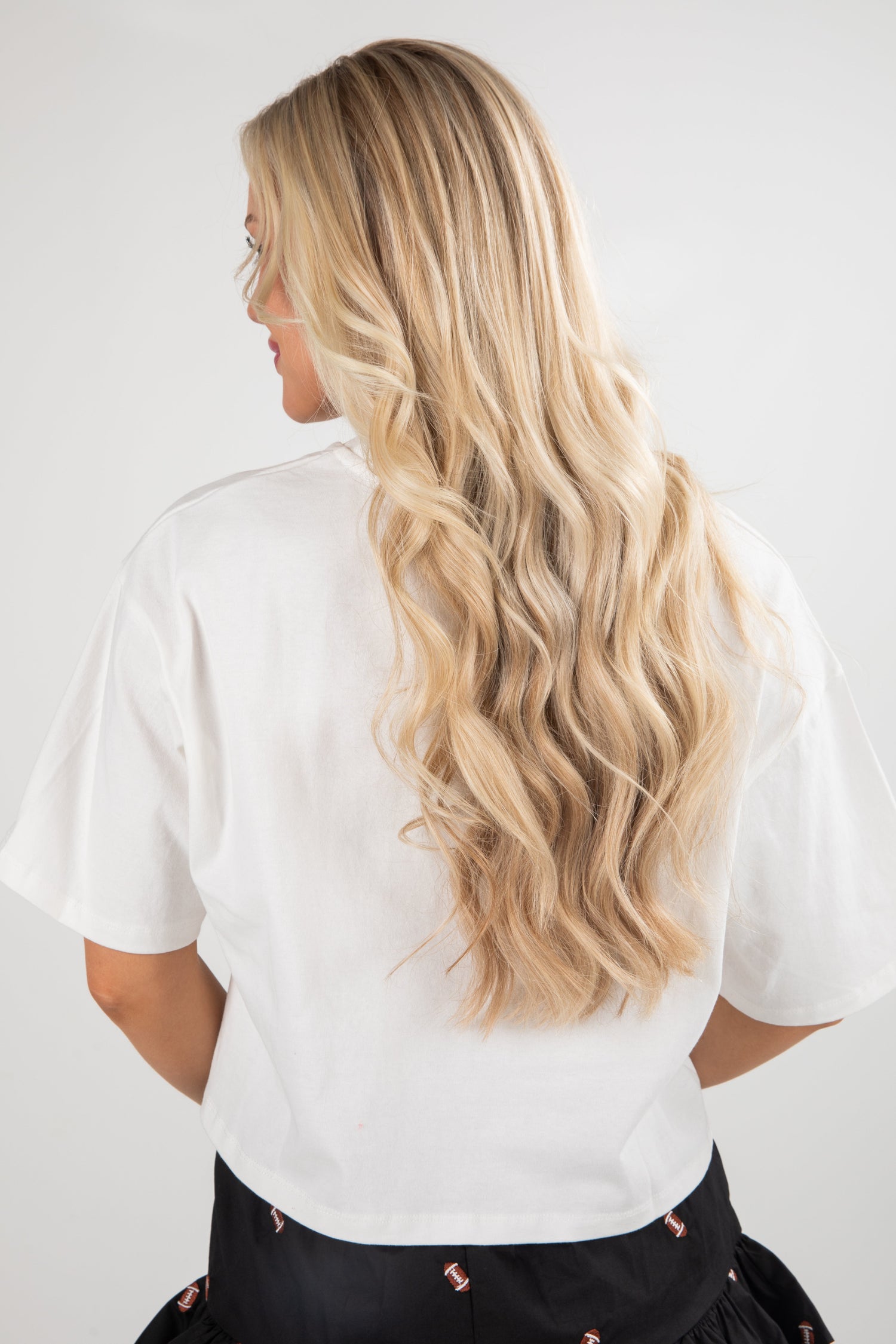 Person with long blonde hair wearing a white shirt against a plain background