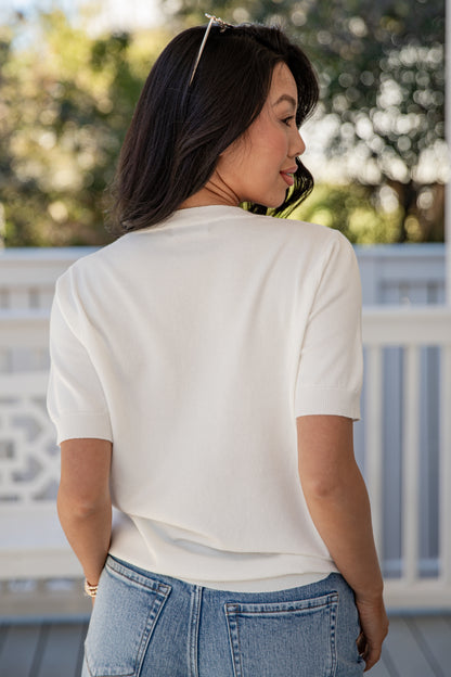 Woman wearing a white shirt and blue jeans on a blurred outdoor background