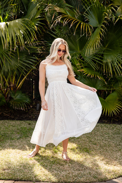 Woman in a white dress standing in front of green foliage