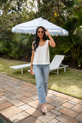 Woman standing under a striped umbrella in a garden setting