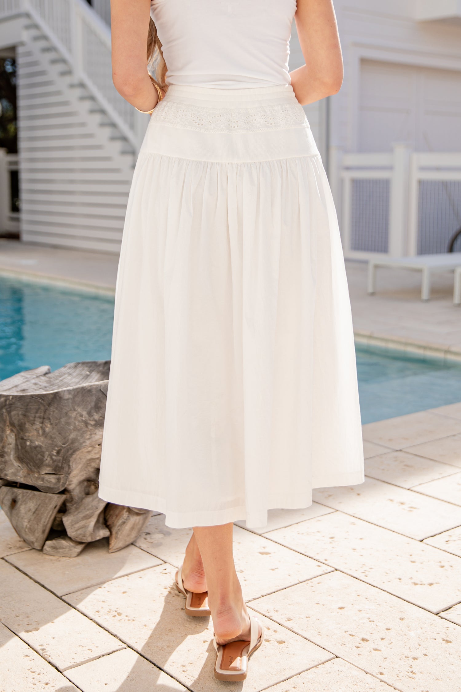 Person wearing a white dress by a poolside
