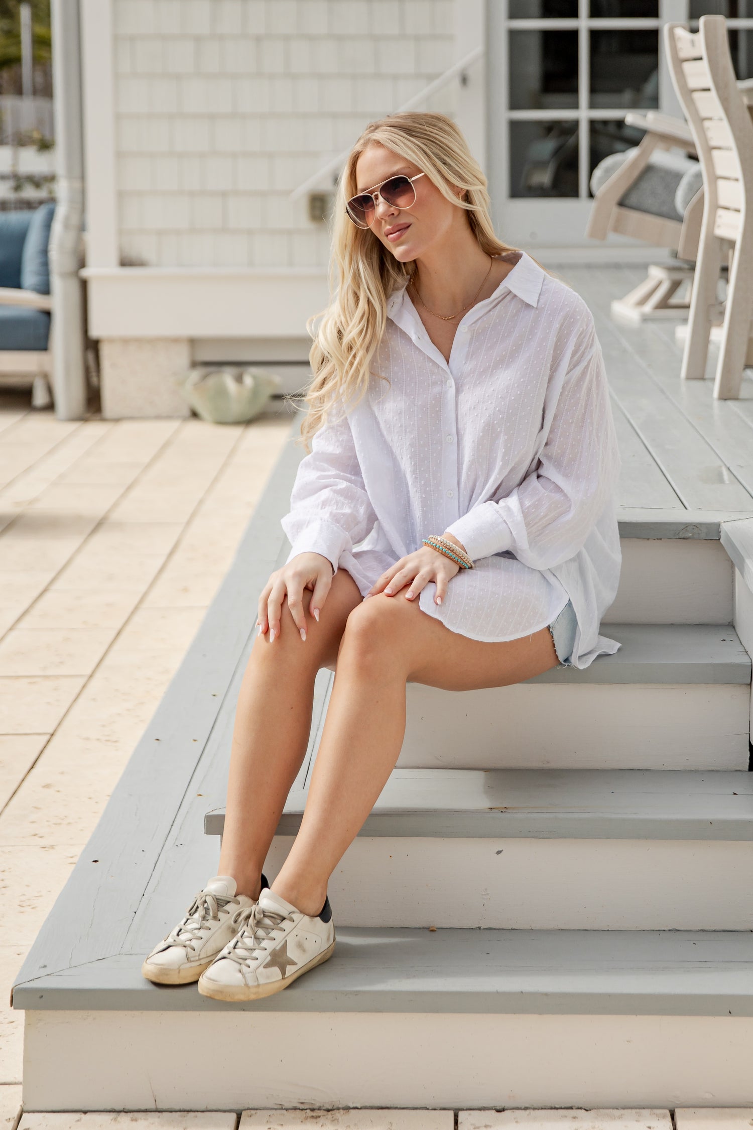 Woman in a white shirt and shorts sitting on steps outdoors
