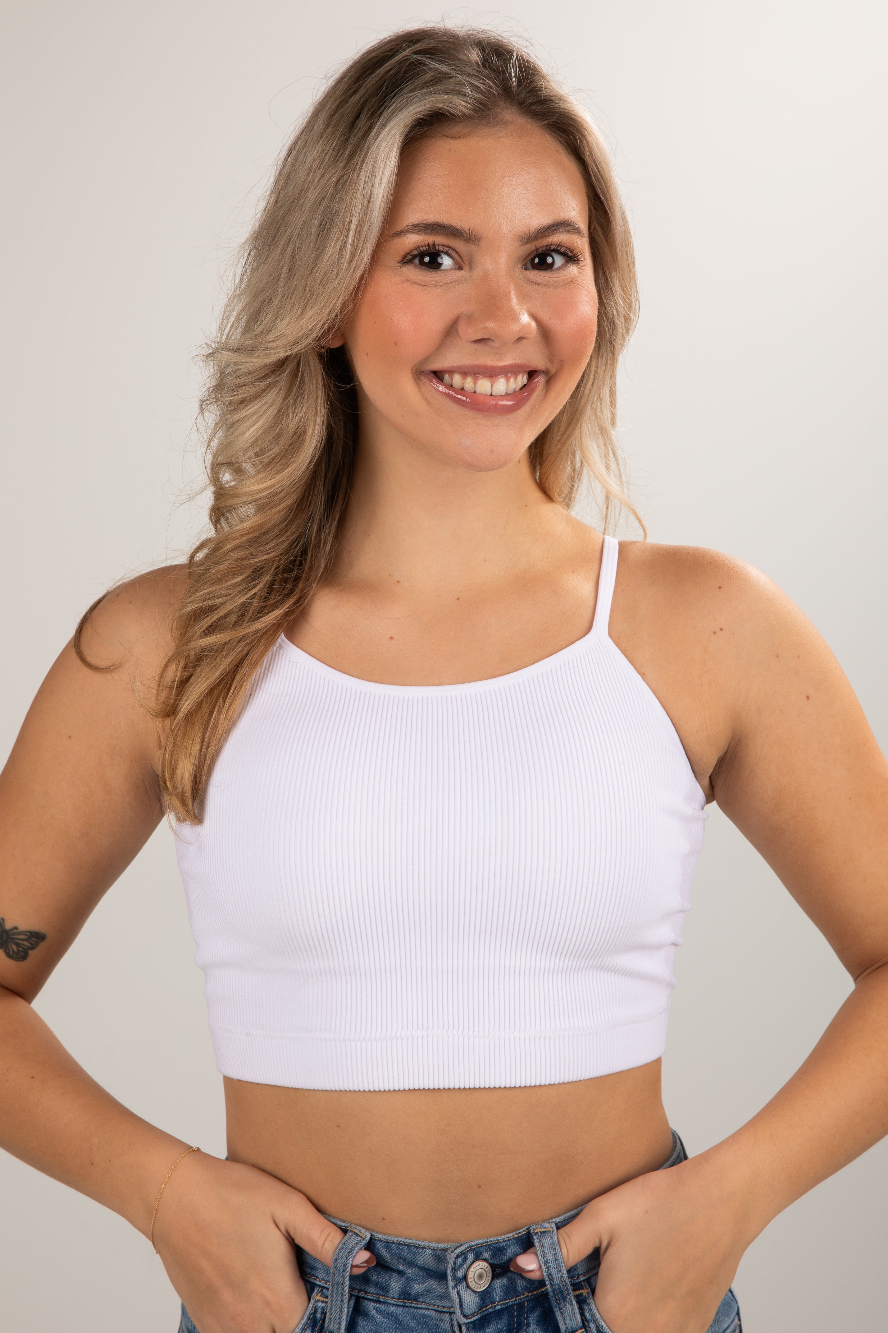 Woman wearing a white crop top against a plain background
