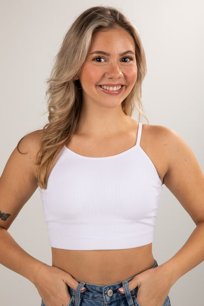 Woman wearing a white crop top against a plain background