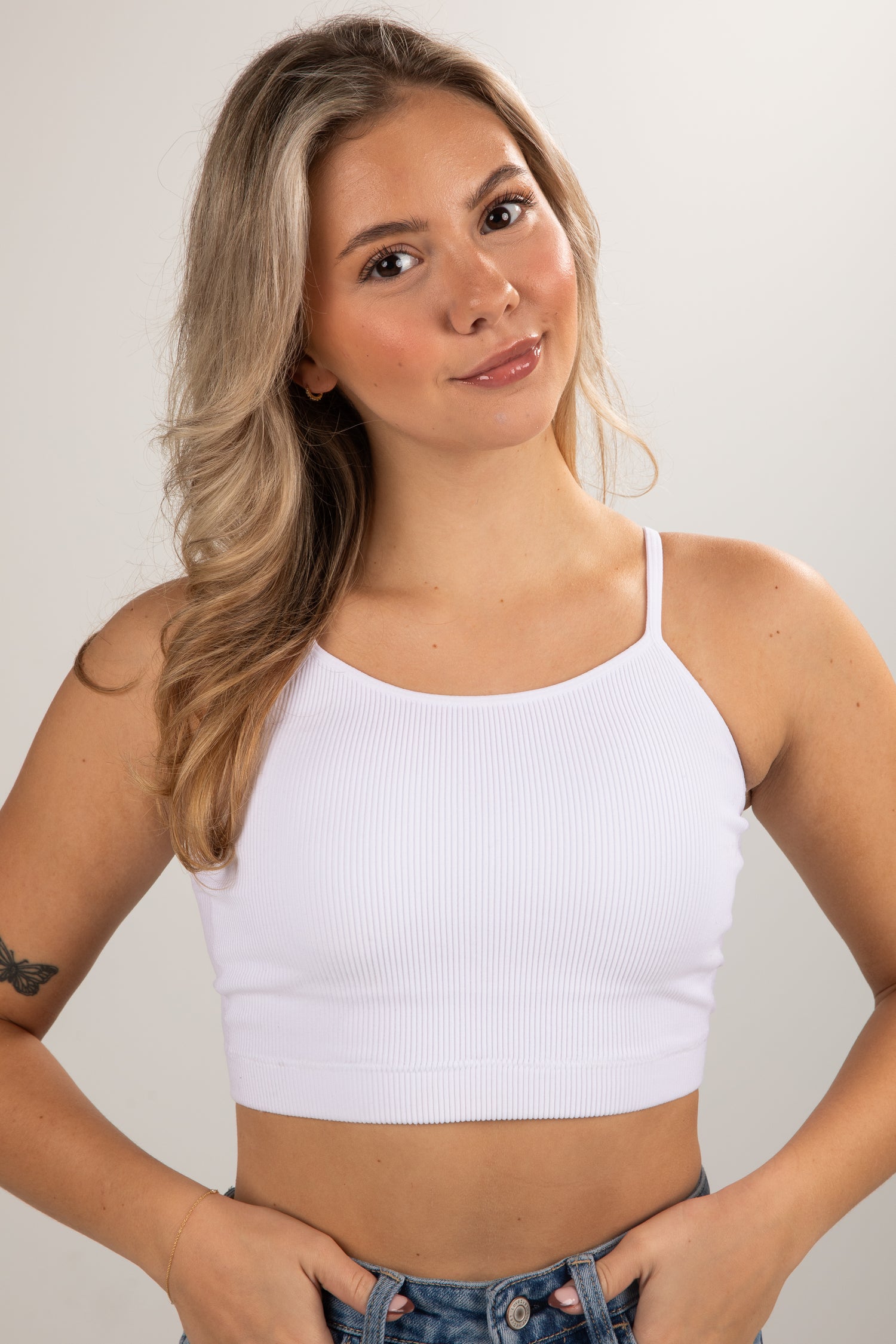 Woman wearing a white crop top against a plain background