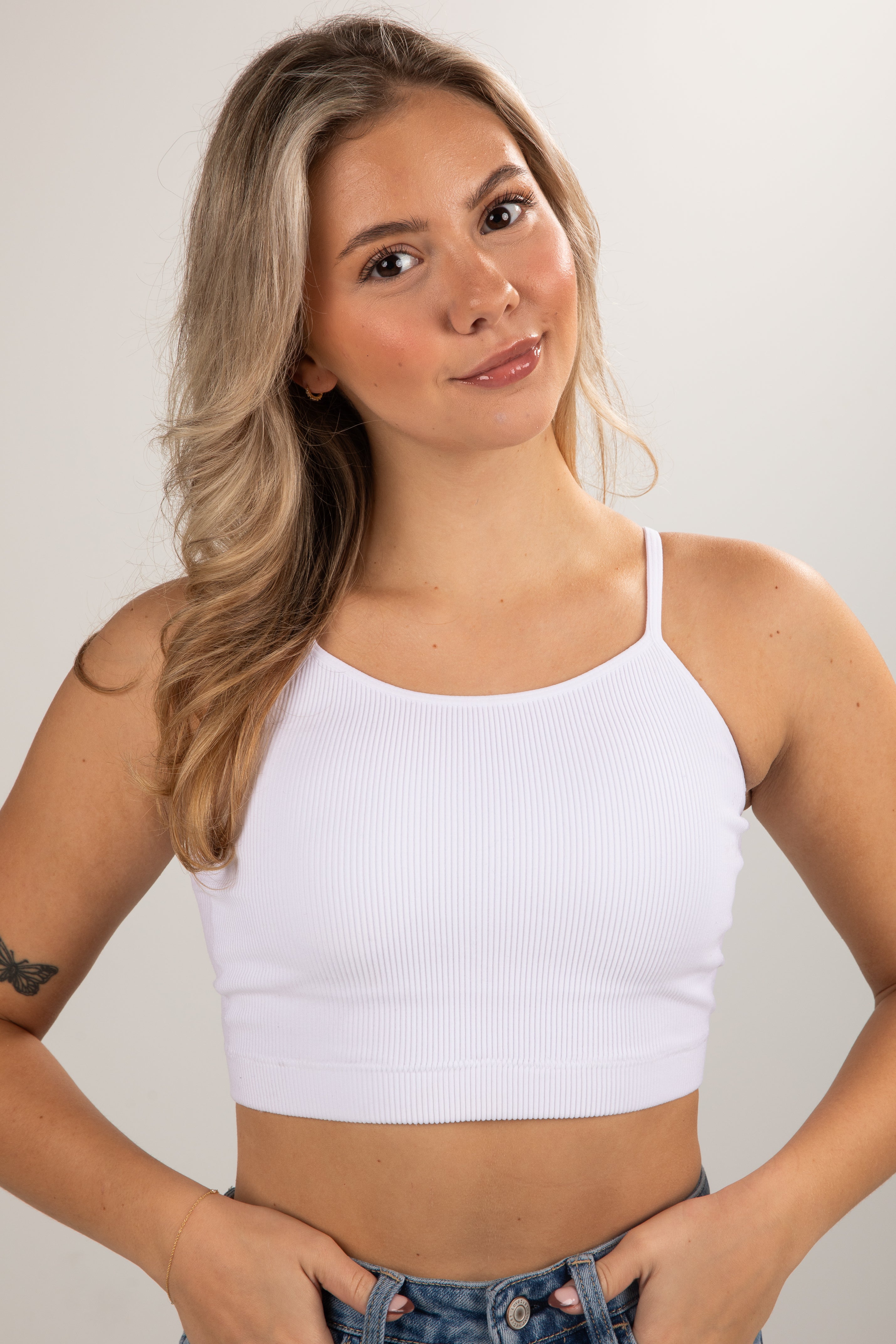 Woman wearing a white crop top against a plain background