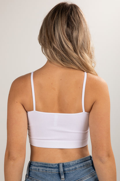 Person wearing a white crop top and blue jeans against a plain background