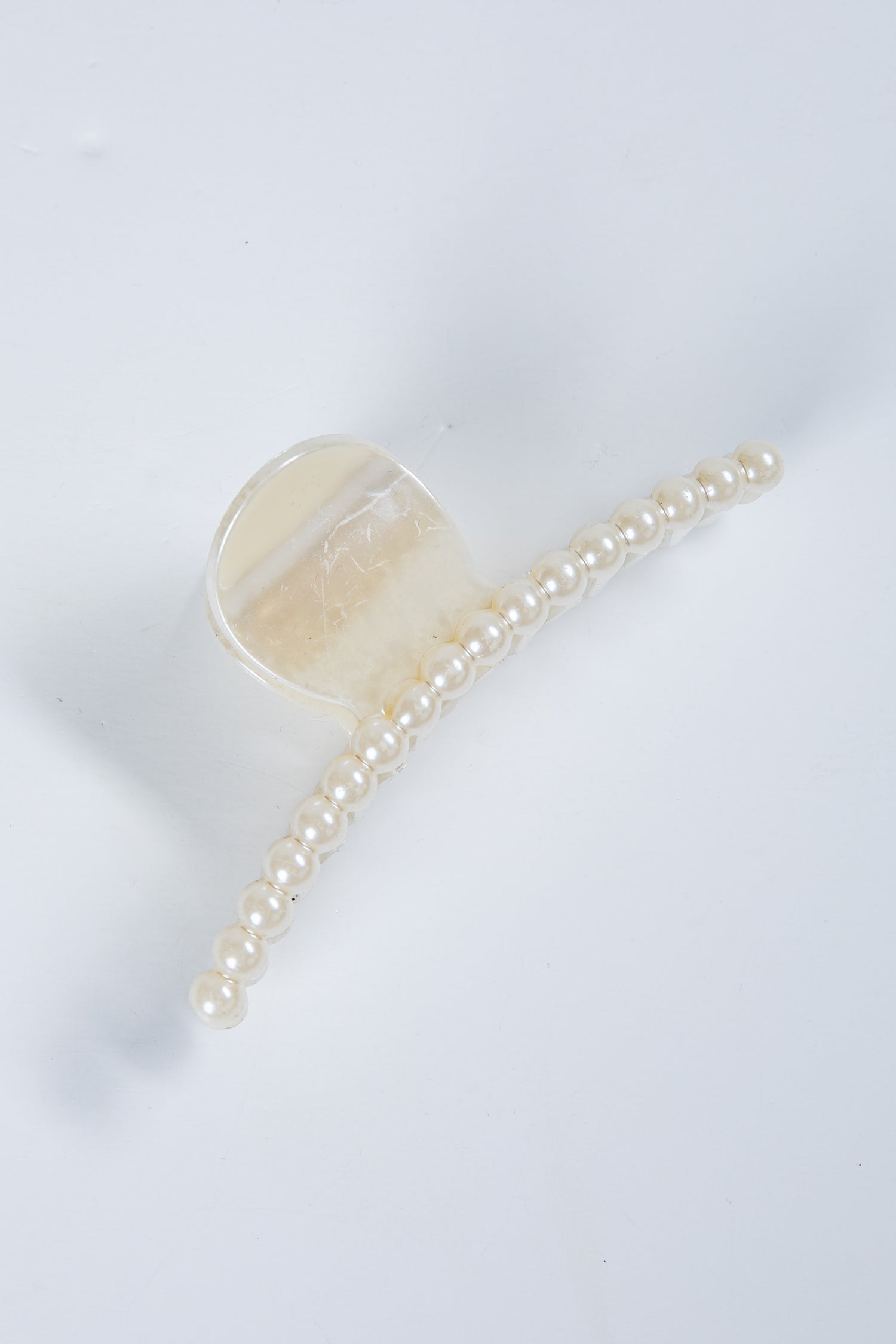 Transparent hair clip with a chain of pearls on a white background
