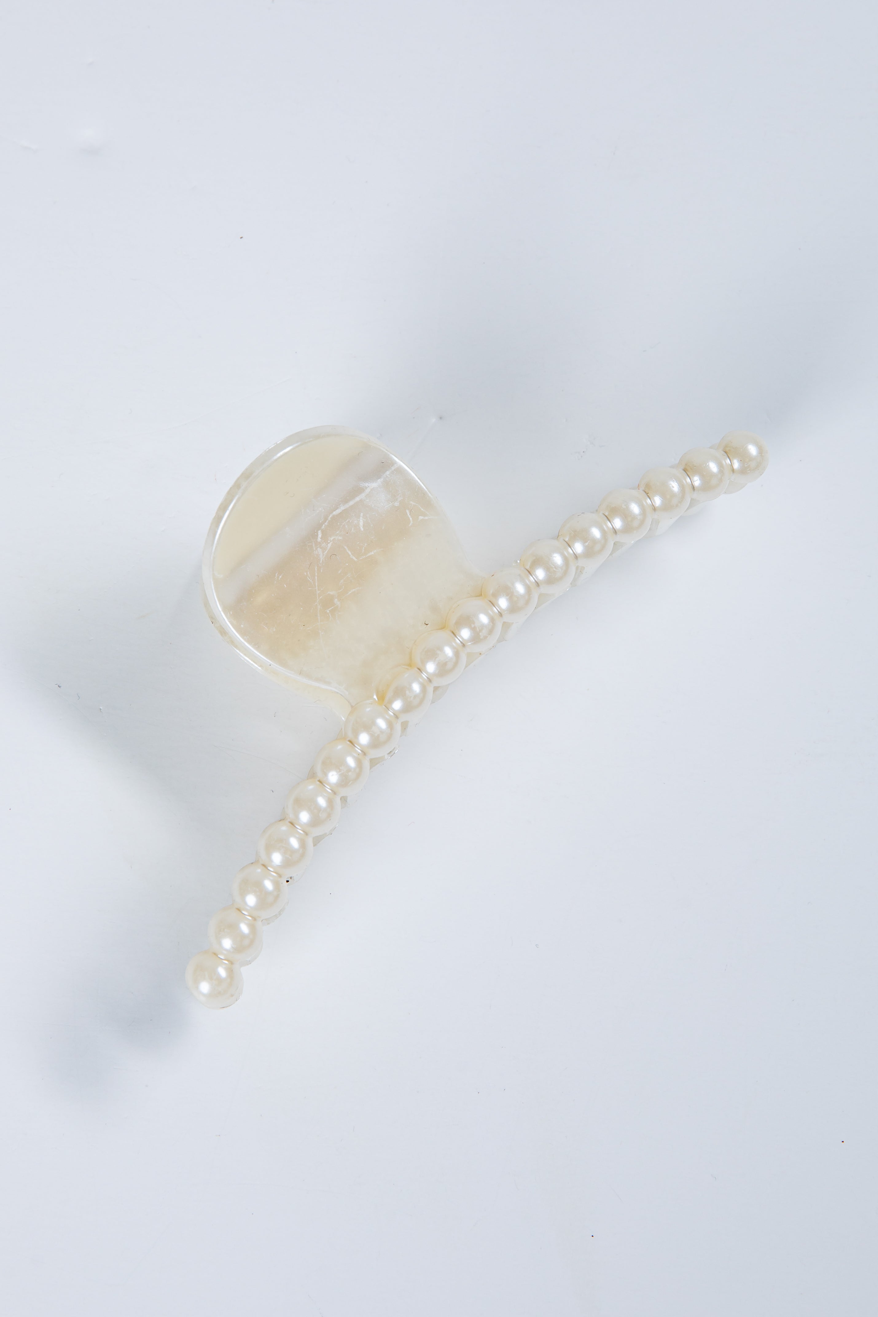 Transparent hair clip with a chain of pearls on a white background