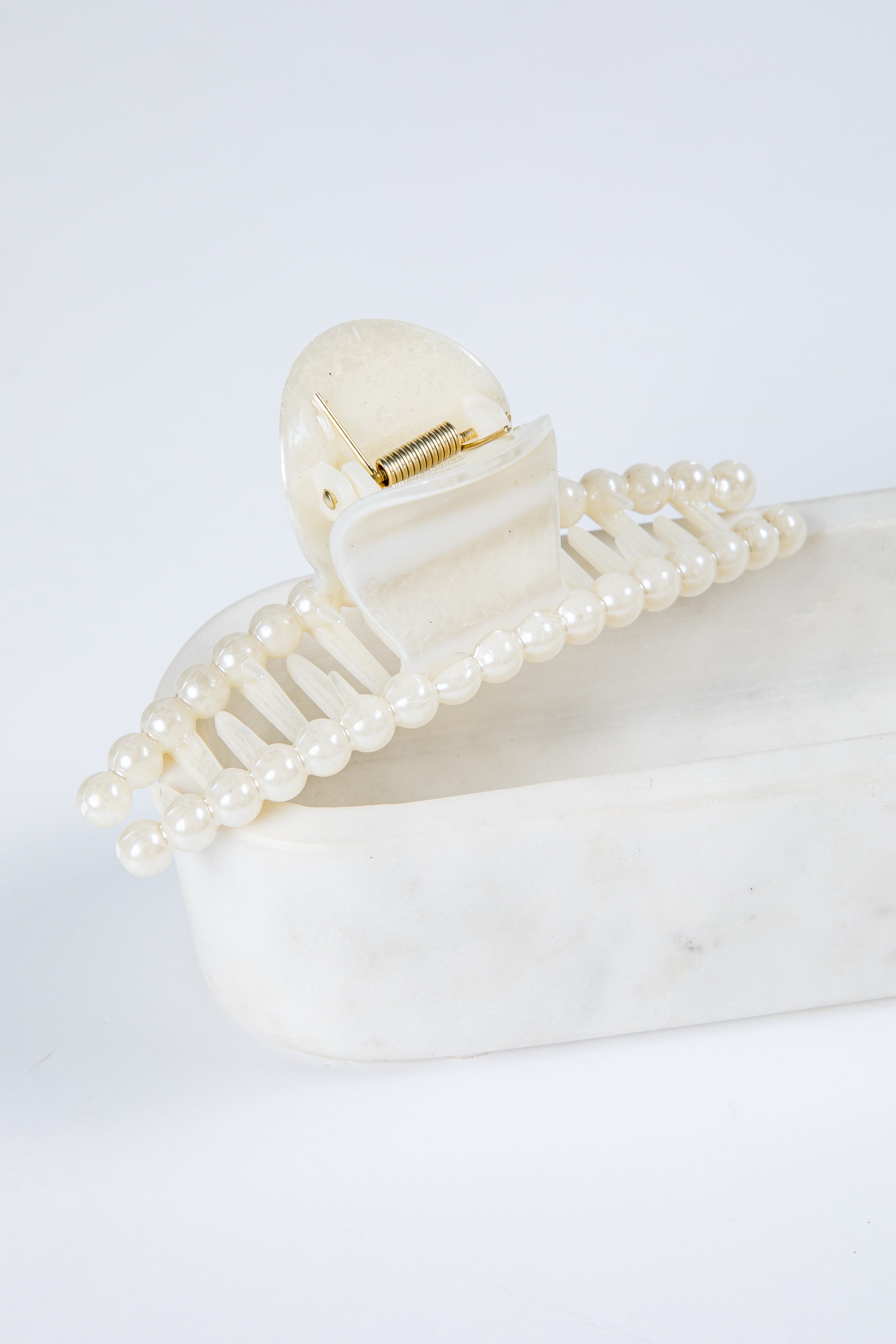 Pearl hair clip on a white surface with a light gray background