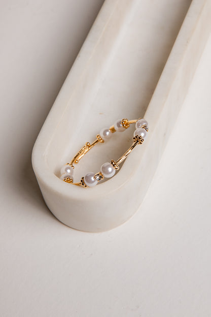 Gold hoop earring with pearls on a white background