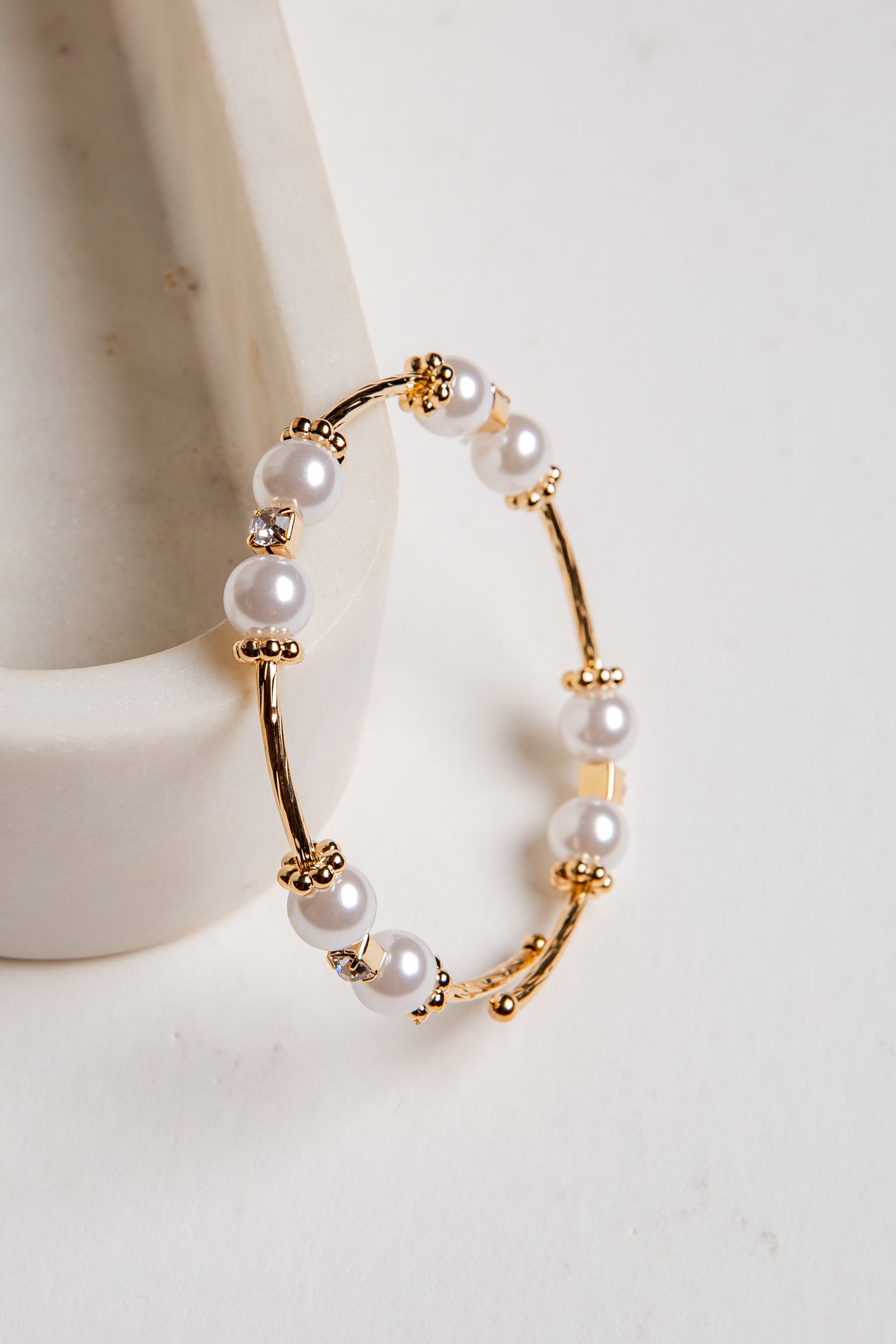 Gold hoop earrings with pearls on a white background