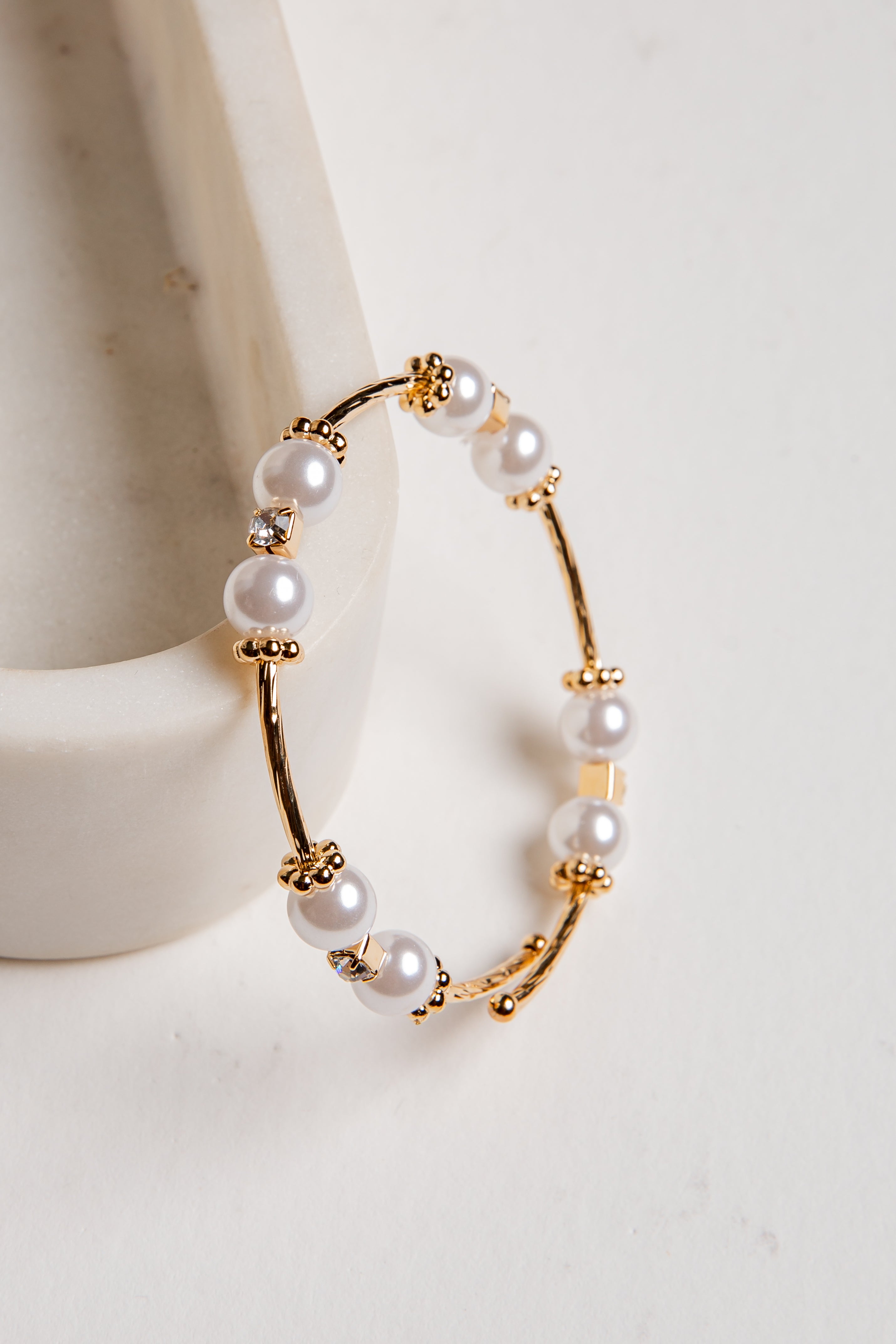 Gold hoop earrings with pearls on a white background