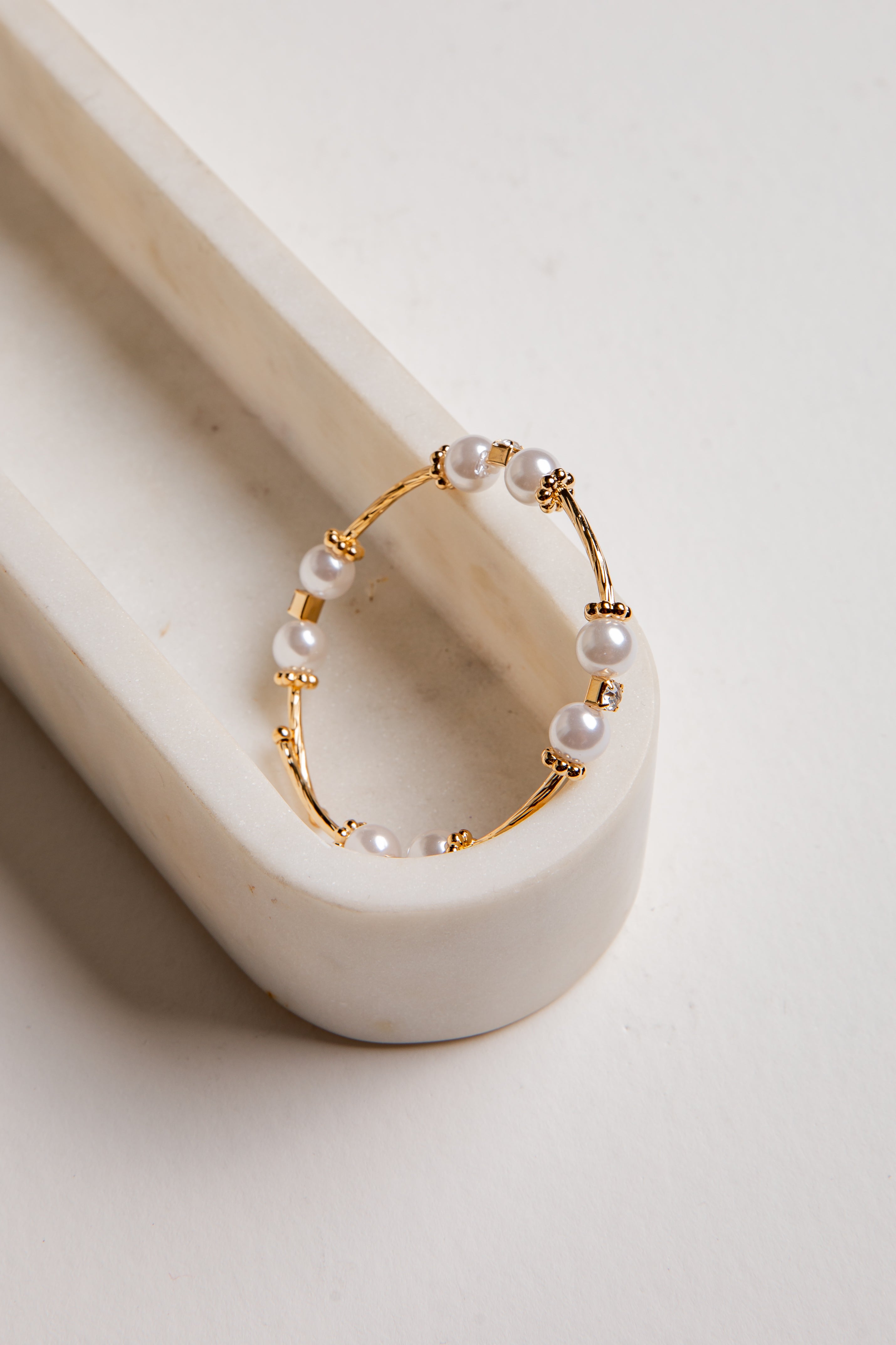 Gold hoop earring with pearls on a white surface