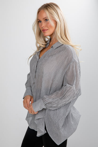 Woman wearing a gray checkered shirt against a white background