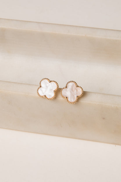 Pair of gold earrings with white stones on a beige surface
