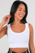 Woman wearing a white tank top against a plain background