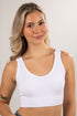 Woman wearing a white tank top against a plain background